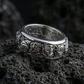 Load image into Gallery viewer, Polished silver rose spinner ring displayed on volcanic stone background highlighting crisp engraved roses, smooth edges, and clean reflective finish
