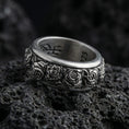Load image into Gallery viewer, Oxidized spinning rose band ring photographed on volcanic rock showcasing deep floral relief, antique patina, and fidget-friendly rotating design