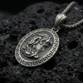 Load image into Gallery viewer, Oxidized 925 sterling silver Medusa coin pendant on volcanic rock, Greek key border medallion with raised goddess profile relief