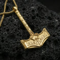 Load image into Gallery viewer, Gold plated Mjolnir pendant on volcanic rock, premium studio scene, Viking amulet with detailed rune engraving