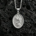 Load image into Gallery viewer, Polished silver phoenix medallion necklace on volcanic rock, crisp raised flame-feather relief and smooth oval frame, close-up