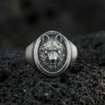 Load image into Gallery viewer, Oxidized sterling silver wolf signet ring on volcanic rock, oval face with detailed wolf head relief and dark recessed background, macro jewelry photo