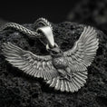 Load image into Gallery viewer, Oxidized owl pendant with spread wings on textured volcanic rock, macro close-up, dark premium studio lighting