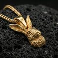 Load image into Gallery viewer, Gold plated rabbit head pendant displayed on porous volcanic rock surface, close-up studio composition, sharp fur texture and bail