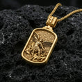 Load image into Gallery viewer, Gold plated Archangel Michael dog tag pendant displayed on porous volcanic rock surface, close-up studio composition, detailed angel wings and sword relief