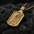 Load image into Gallery viewer, Gold plated Saint Andrew dog tag pendant displayed on textured volcanic rock, detailed apostle figure with cross, luxury studio composition
