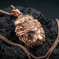 Load image into Gallery viewer, Rose gold plated lion head pendant on volcanic rock surface, detailed mane texture and crowned motif, crisp macro product composition