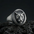 Load image into Gallery viewer, Oxidized sterling silver leopard signet ring on textured volcanic rock, macro close-up showing round face with raised big cat portrait and dark recessed background