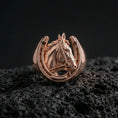 Load image into Gallery viewer, Rose gold plated horseshoe horse ring on volcanic rock, sharp macro product photo showcasing the horse head relief inside the horseshoe frame