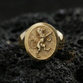 Load image into Gallery viewer, Gold plated heraldic lion signet ring on volcanic rock in a dark studio setting, detailed macro shot emphasizing the raised lion figure and premium shine