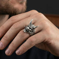Load image into Gallery viewer, Sterling silver oni mask ring in an oxidized finish worn on finger, horned Japanese yokai demon face visible, dark streetwear lifestyle close-up