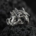 Load image into Gallery viewer, Detailed Minotaur ring crafted in oxidized sterling silver, muscular bull-headed beast holding double axe, macro product shot on textured volcanic rock background
