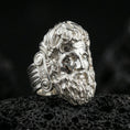 Load image into Gallery viewer, Polished silver Zeus ring featuring sculpted god portrait and refined facial expression, centered close-up jewelry photo on dark porous volcanic stone
