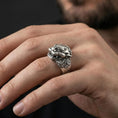 Load image into Gallery viewer, Oxidized sterling silver Foo Dog ring worn on finger, powerful Chinese guardian lion head with ornate scrollwork, masculine lifestyle hand shot