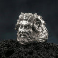 Load image into Gallery viewer, Polished silver Czernobog ring featuring sculpted horned god portrait and intricate hair texture, centered close-up on dark porous volcanic stone