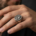 Load image into Gallery viewer, Oxidized 925 sterling silver Medusa ring worn on finger, bold snake hair profile design with Greek key border, masculine lifestyle hand shot