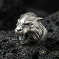Load image into Gallery viewer, Detailed werewolf head ring crafted in oxidized sterling silver, snarling wolf face with sharp fangs, macro product shot on textured volcanic rock background
