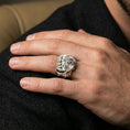 Load image into Gallery viewer, Polished sterling silver dragon skull ring on a human finger, detailed skull pile and dragon design, statement signet ring
