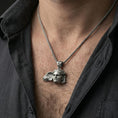 Load image into Gallery viewer, Oxidized sterling silver Hypnos pendant worn on neck on a braided chain, centered chest framing, moody lifestyle studio shot