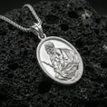Load image into Gallery viewer, Polished silver Jesus Christ medallion necklace on dark volcanic stone, crisp engraved figure and smooth oval bezel, premium close-up composition