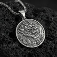 Load image into Gallery viewer, Oxidized 925 sterling silver Chinese dragon round pendant on textured volcanic rock, intricate Asian dragon engraving and wave motifs, macro studio shot