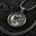 Load image into Gallery viewer, Oxidized sterling silver Mortal Kombat dragon pendant on volcanic rock, round medallion with raised dragon emblem, macro studio lighting