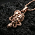 Load image into Gallery viewer, Rose gold plated Medusa skull necklace on dark volcanic stone, serpent-wrapped pendant with gothic myth design and premium shine