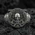 Load image into Gallery viewer, Oxidized sterling silver Viking warrior ring on black volcanic rock, macro close-up showing skull helmet relief, crossed axes and deep shadowed engravings