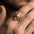 Load image into Gallery viewer, Rose gold plated laurel wreath skull ring on a finger, close-up lifestyle photo showcasing warm finish, leaf crown definition and antique-inspired contrast