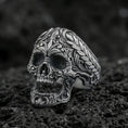 Load image into Gallery viewer, Oxidized sterling silver baroque skull ring with ornate floral filigree and braided border on black volcanic rock, macro close-up with deep shadowed detail
