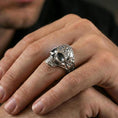 Load image into Gallery viewer, Polished silver ornate skull ring worn on the finger, wearable photo highlighting reflective metal and carved floral detailing