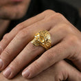 Load image into Gallery viewer, Gold plated skull ring with baroque scrollwork worn on a finger, lifestyle image emphasizing warm tone and bold gothic statement look
