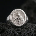 Load image into Gallery viewer, Polished silver Greek warrior signet ring with high-relief helmeted figure and crisp highlights, macro close-up on textured volcanic stone