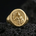 Load image into Gallery viewer, Gold plated Spartan soldier signet ring with spear-and-shield design and Greek key side detail, product photo on porous volcanic rock