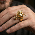 Load image into Gallery viewer, Gold plated demon skull ring worn on a finger, lifestyle image emphasizing the horn relief and skull face details