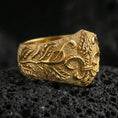 Load image into Gallery viewer, Gold plated fleur-de-lis signet ring with vine engraving and bold crest relief, macro product-only image on black volcanic rock