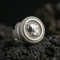 Load image into Gallery viewer, Polished silver coin-style ring featuring a helmeted warrior head and striped background texture, close-up shot on volcanic stone