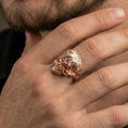 Load image into Gallery viewer, Rose gold plated gothic skull ring on a finger, lifestyle shot showing the engraved floral pattern and sculpted skull profile