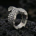 Load image into Gallery viewer, Oxidized sterling silver eagle wing open ring with layered feather texture and sculpted bird head, macro product photo on black volcanic rock