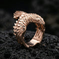 Load image into Gallery viewer, Rose gold plated wing open ring with engraved feather layers and a pointed bird head design, close-up product shot on volcanic rock