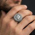 Load image into Gallery viewer, Oxidized Greek coin signet ring worn on a finger, close-up lifestyle shot highlighting the classical portrait relief and rope bezel