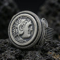 Load image into Gallery viewer, Oxidized sterling silver Greek coin ring featuring a classical profile portrait framed by a rope border, macro photo on black volcanic rock