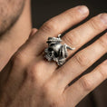 Load image into Gallery viewer, Oxidized horned skull ring worn on a finger, close-up lifestyle shot highlighting the curved horns and skull relief