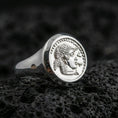 Load image into Gallery viewer, Polished silver Greek coin ring featuring a raised portrait relief and smooth signet band, close-up on volcanic stone