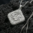 Load image into Gallery viewer, Polished silver koi fish necklace on volcanic rock, crisp scale texture and wave pattern border, close-up lighting
