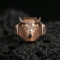 Load image into Gallery viewer, Rose gold plated bull head signet ring on volcanic rock, textured lava stone background, bold horns and sculpted face detail