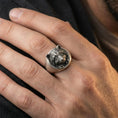 Load image into Gallery viewer, Oxidized raccoon head signet ring worn on finger, lifestyle close-up, round face centered with rugged masculine styling