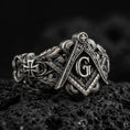 Load image into Gallery viewer, Oxidized sterling silver Masonic signet ring with square and compass emblem, “G” letter and ornate scrollwork, on black volcanic rock