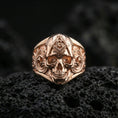 Load image into Gallery viewer, Rose gold plated Freemason skull ring with compass G emblem and carved scrollwork shoulders, macro photo on black volcanic rock