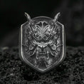 Load image into Gallery viewer, Oxidized sterling silver oni mask signet ring with horned Japanese demon face and deep relief texture, macro on black volcanic rock